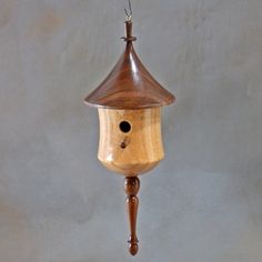 a wooden bird house hanging from a chain