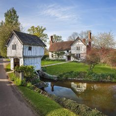 an old white house next to a river