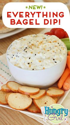 a bowl of dip surrounded by crackers and carrots on a plate with the words, everything bagel dip