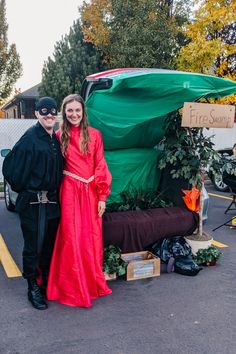 two people standing in front of a car with a green tarp covering it's hood