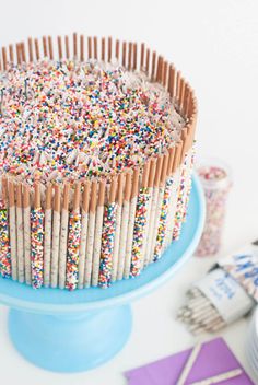 a birthday cake with sprinkles and candles on a blue plate next to other decorations