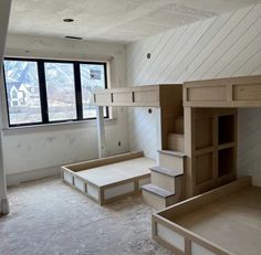 an unfinished room with stairs and shelves in the middle, next to a large window