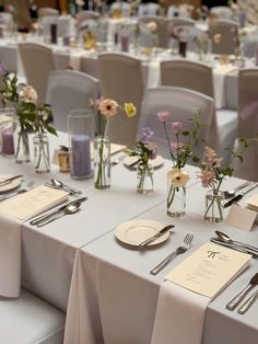 the table is set with silverware and flowers in glass vases on each side