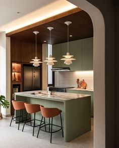 a kitchen with green cabinets and stools next to an island in the middle of it