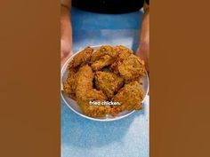 a person holding a plate full of fried chicken