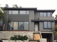 a large gray house with lots of windows on the top floor and stairs leading up to it