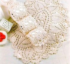 crocheted doily and other items on a white tablecloth with red berries