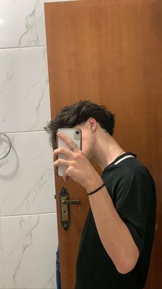 a young man taking a selfie in front of a mirror with his cell phone