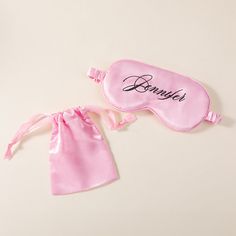 two pink eye masks with the word bennie written on them, one in satin bag