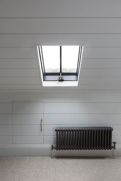 an empty room with a radiator and skylight in the ceiling above it