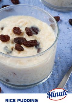 rice pudding with raisins in a glass bowl on a blue tablecloth next to two spoons