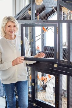 a woman standing in front of a bird cage