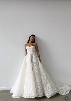 a woman in a wedding dress leaning against a wall