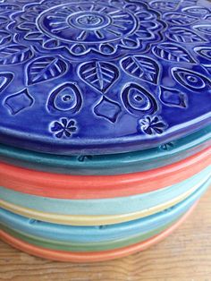 a stack of colorful plates sitting on top of a wooden table next to each other