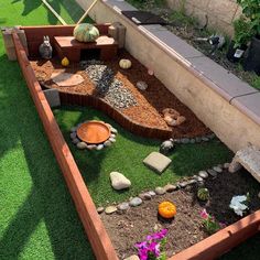 an outdoor garden with rocks and plants in the center, including pumpkins on the ground