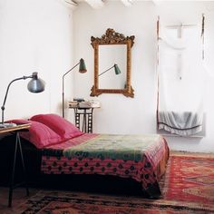 a bed sitting in a bedroom next to a mirror and table with lamps on it