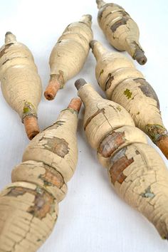 four old wooden carrots are lined up on a white tablecloth with paint peeling off them