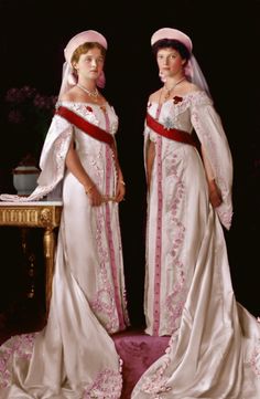 two women in wedding dresses standing next to each other on a pink carpeted floor