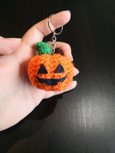 a hand holding a small orange pumpkin keychain