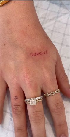 a woman's left hand with the word love written on it and two wedding bands