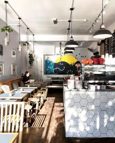 the interior of a restaurant with tables, chairs and artwork hanging from the ceiling above