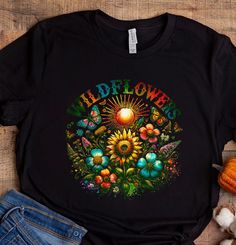 Embrace your wild and free spirit with our women's wildflower graphic tee (or sweatshirt). This beautifully designed piece features a vibrant array of wildflowers, symbolizing strength, resilience, and natural beauty. Whether you're adventuring outdoors or cozying up inside, this tee (or sweatshirt) is a reminder to bloom wherever you're planted.  T-Shirt:      Indulge in the luxurious softness and durability of 100% ring-spun cotton, providing a comfortable feel against the skin. Ideal for anyone looking for a premium unisex shirt. Pre-shrunk Sweatshirt:    This sweatshirt offers the ultimate comfort and durability, making it suitable for various seasons. It's warm enough to be worn alone during cool weather, but it can also be layered for added warmth during the colder months. Unisex com Hippie Graphic Print T-shirt For Fall, Hippie Crew Neck T-shirt For Fall, Black Hippie Top With Letter Print, Hippie Graphic Print Top For Fall, Black Bohemian T-shirt With Letter Print, Multicolor Hippie T-shirt With Letter Print, Hippie Multicolor Letter Print T-shirt, Multicolor Graphic Print T-shirt For Fall, Bohemian Multicolor Graphic Print T-shirt