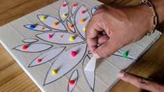 a person's hand is holding a piece of paper with colored dots on it