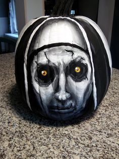 a painted pumpkin with an image of a woman's face and eyes on it