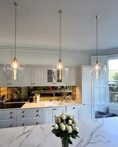 a kitchen with marble counter tops and pendant lights hanging from the ceiling over the island