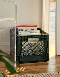 a green crate sitting on top of a hard wood floor next to a white door