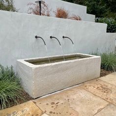 an outdoor fountain with three faucets in the center and water running from it