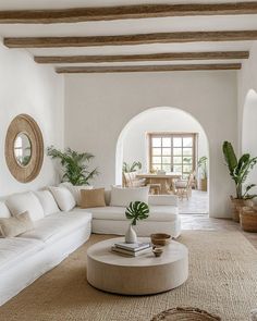 a living room filled with white furniture and plants