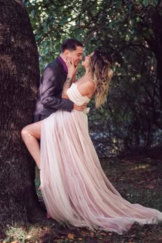 a man and woman standing next to each other near a tree