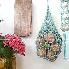 there is a vase with flowers and fruit in it next to a wall hanging bag