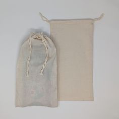 two bags are sitting next to each other on a white surface, one is empty and the other has a drawstring