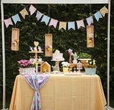 a yellow and white checkered table cloth with bunting on it, some potted plants and other decorations