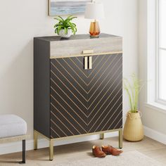 a black and gold cabinet next to a white chair in a room with a painting on the wall