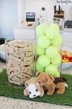 tennis balls and stuffed animals are sitting on the counter in front of a glass vase