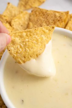 a tortilla chip being dipped with cheese dip