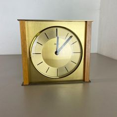 a gold clock sitting on top of a table next to a white wall and floor