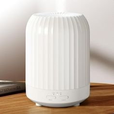 a white speaker sitting on top of a wooden table