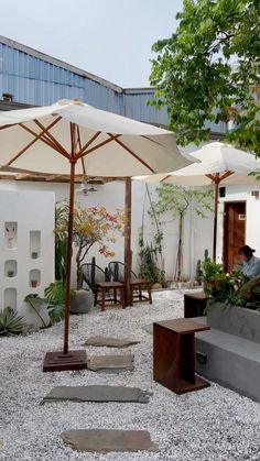 an outdoor seating area with white umbrellas and graveled ground in the foreground