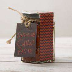 a jar filled with chili paste sitting on top of a white wooden table next to a sign