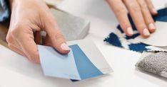 a person is working on some blue and white paint swatches with their hands over them