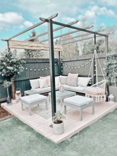 an outdoor living area with white furniture and lights