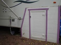 an rv parked in front of a white building with purple trim on the door and windows