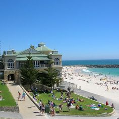 many people are on the beach and in the water at this resort near the ocean