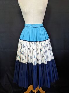 "This 50s cotton fiesta skirt is very full, over a circle actually, and has the most wonderful print of Indian Chief headdresses on the middle tier. The colors of turquoise, cream, navy, and red coral make a perfect match for Indian jewelry. Inside the waistband there are rows of rubber stitching to keep your blouse tucked in while dancing. The colors are bright and unfaded, there is a small side zipper, and the eyes for the hooks were moved to make the waistband tighter. Except for some slight Retro Blue Cotton Skirt, Chiefs Headdress, Indian Chief, A Circle, Red Coral, Indian Jewelry, Skirt Length, Tie Dye Skirt, Perfect Match