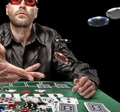 a man wearing red glasses sitting at a table with playing cards and dices in front of him