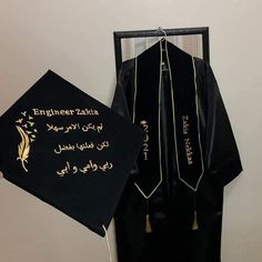 a black graduation gown with gold writing on it next to a sign that says engineer zaria